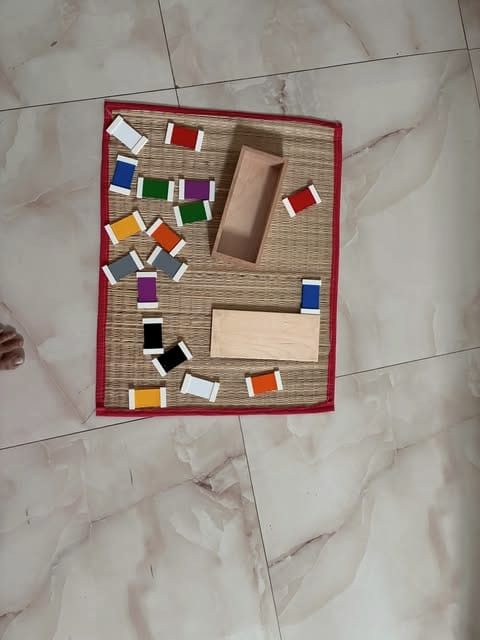 Coloured tablets arranged around the edge of a mat beside their wooden box.